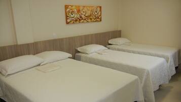 A hotel room with three single beds, each with white bedding and pillows. There is a painting on the wall above the beds.