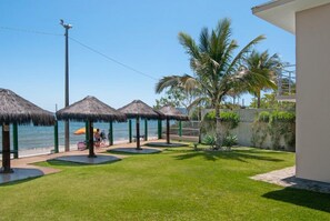 A well-maintained outdoor area with thatched umbrellas, a grassy lawn, and a view of the sea. - Pousada Holiday (Florianópolis)