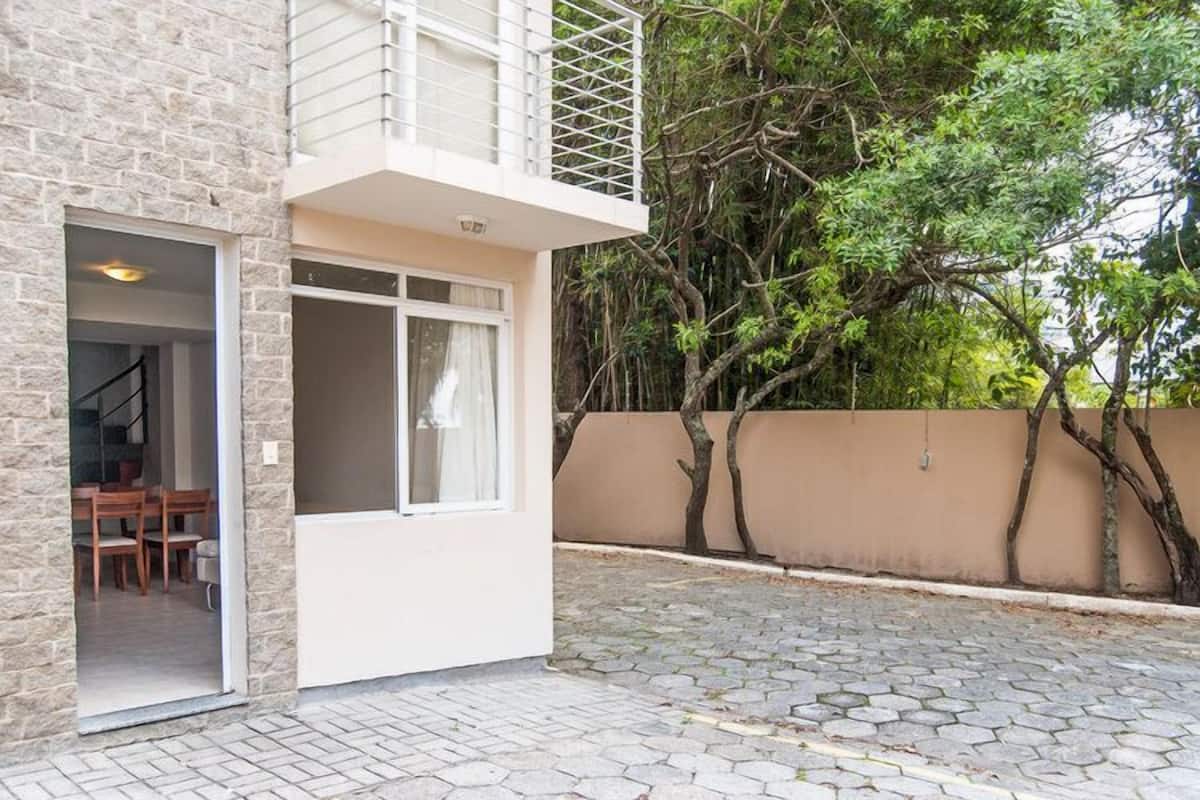 A two-story building with a stone facade, a balcony, and a paved courtyard.