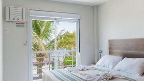 Habitación de hotel con cama, ventana que ofrece vista a palmeras y aire acondicionado de pared.