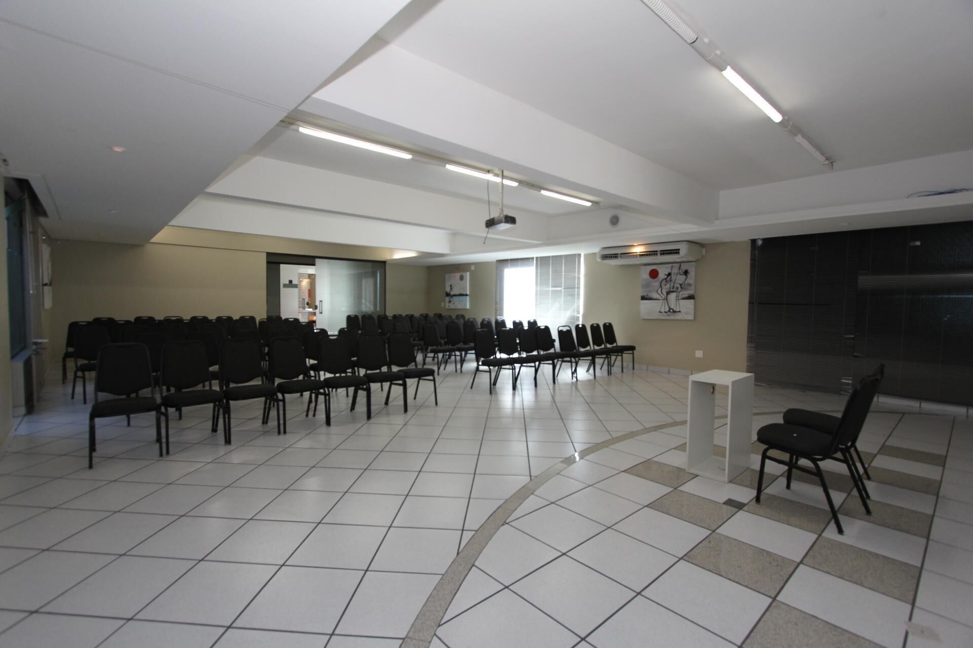 A conference room with rows of chairs, a projector, and a large window.