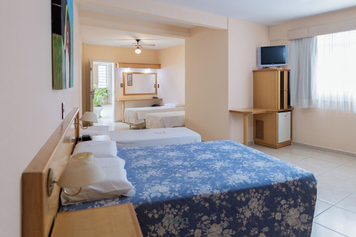 A hotel room with two beds, a television, a desk, and a mirror.