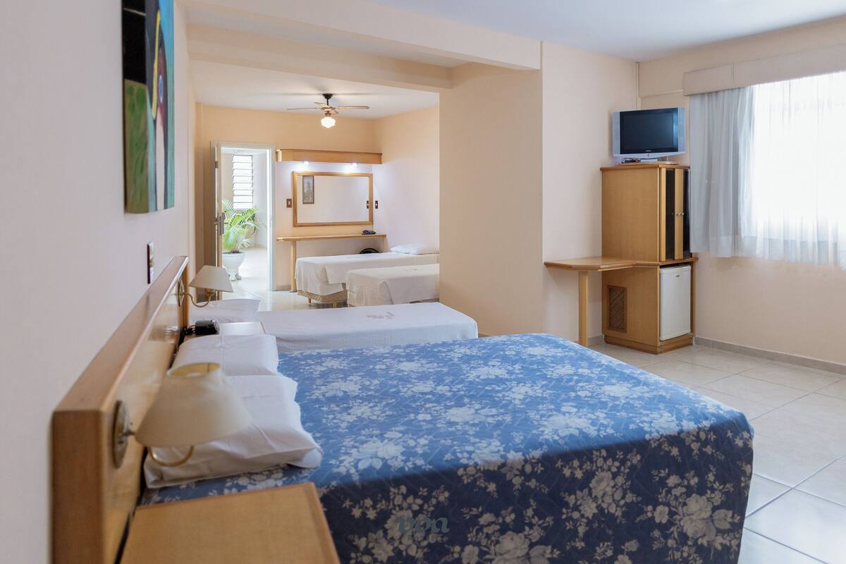 A hotel room with two beds, a television, a desk, and a mirror.