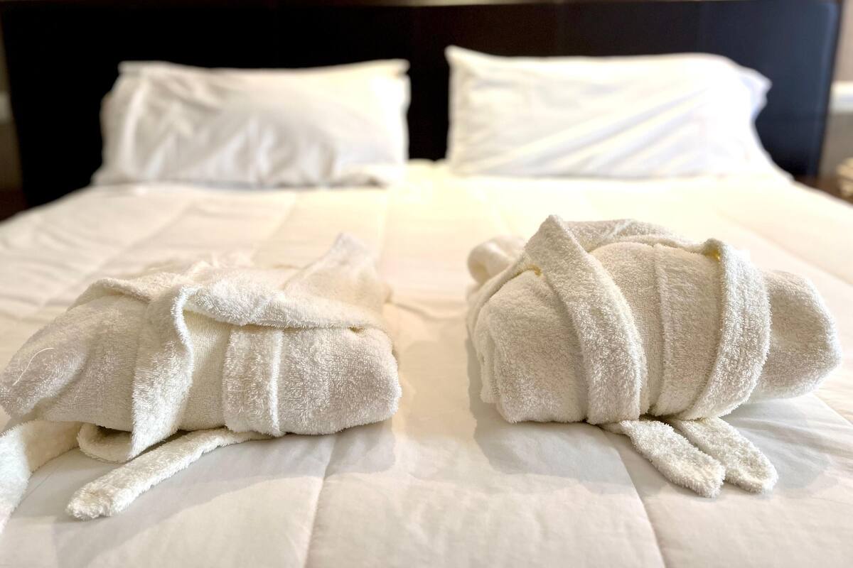 Ein ordentlich gemachtes Bett mit weißen Leinentüchern und zwei in Tierformen gefalteten Handtüchern.