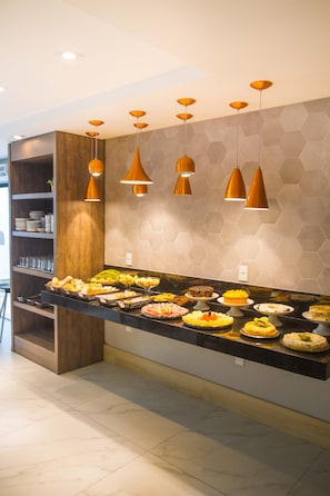 Ein Buffet mit verschiedenen Speisen, Pendelleuchten und einer sechseckigen Wandstruktur.