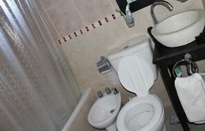 A bathroom with two toilets, a sink, and a shower area. - Cabañas El Secreto (Monte Hermoso)