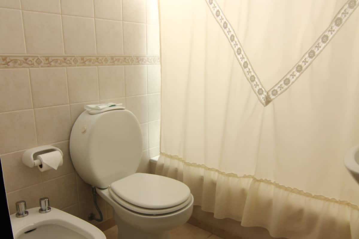 Un baño con inodoro, bidé y cortina de ducha.