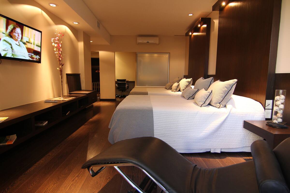 Habitación de hotel con una cama grande, televisión, escritorio y una silla.