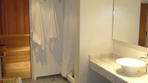 A bathroom with a wooden shower enclosure, a white sink, and a mirror above the sink. - 646 Hotel Balcarce (Balcarce)
