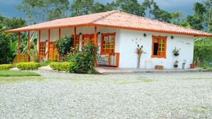 A white building with a red roof and orange accents, surrounded by greenery. - Finca Hotel Fatima (Armenia)