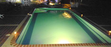 Una piscina al aire libre con borde de ladrillo y una cubierta.