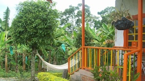 A hammock hanging between trees, a staircase with orange railings, and a well-maintained garden with green bushes and banana plants. - Finca Hotel Fatima (Armenia)