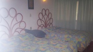 Una stanza con due letti, ognuno con una coperta a fiori, un poggiatesta decorativo e una finestra con tende.