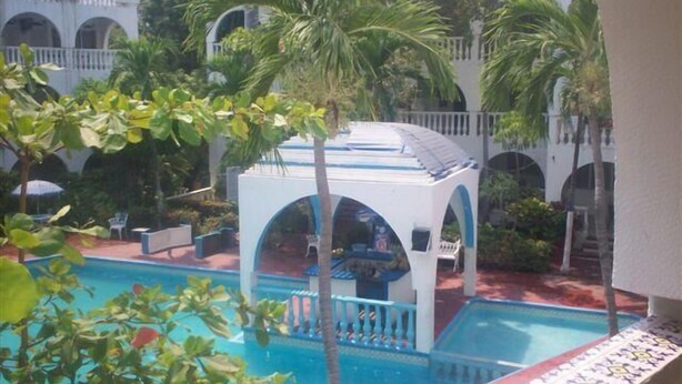 Un'area piscina con gazebo, palme e vista su un edificio ad archi.
