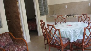 Zona pranzo con tavolo rotondo, quattro sedie, un divano e una cucina sullo sfondo.