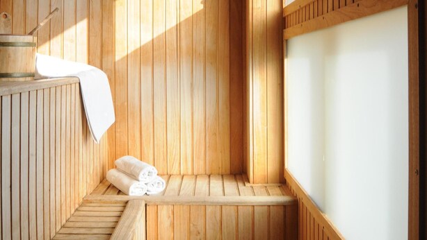 A sauna with wooden walls, a bench, and a window.