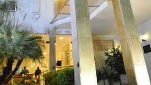 A multi-story hotel with a central atrium, multiple balconies, and a well-lit entrance.