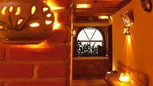 Een smalle gang met een bakstenen muur, een decoratieve metalen pot en een houten plafond.