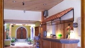 Een houten interieur met een betegelde vloer, een receptiebalie en een deur die naar een andere ruimte leidt.