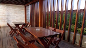 Une terrasse en bois avec une table et des bancs, entourée d’une clôture en bois et d’un mur en briques.