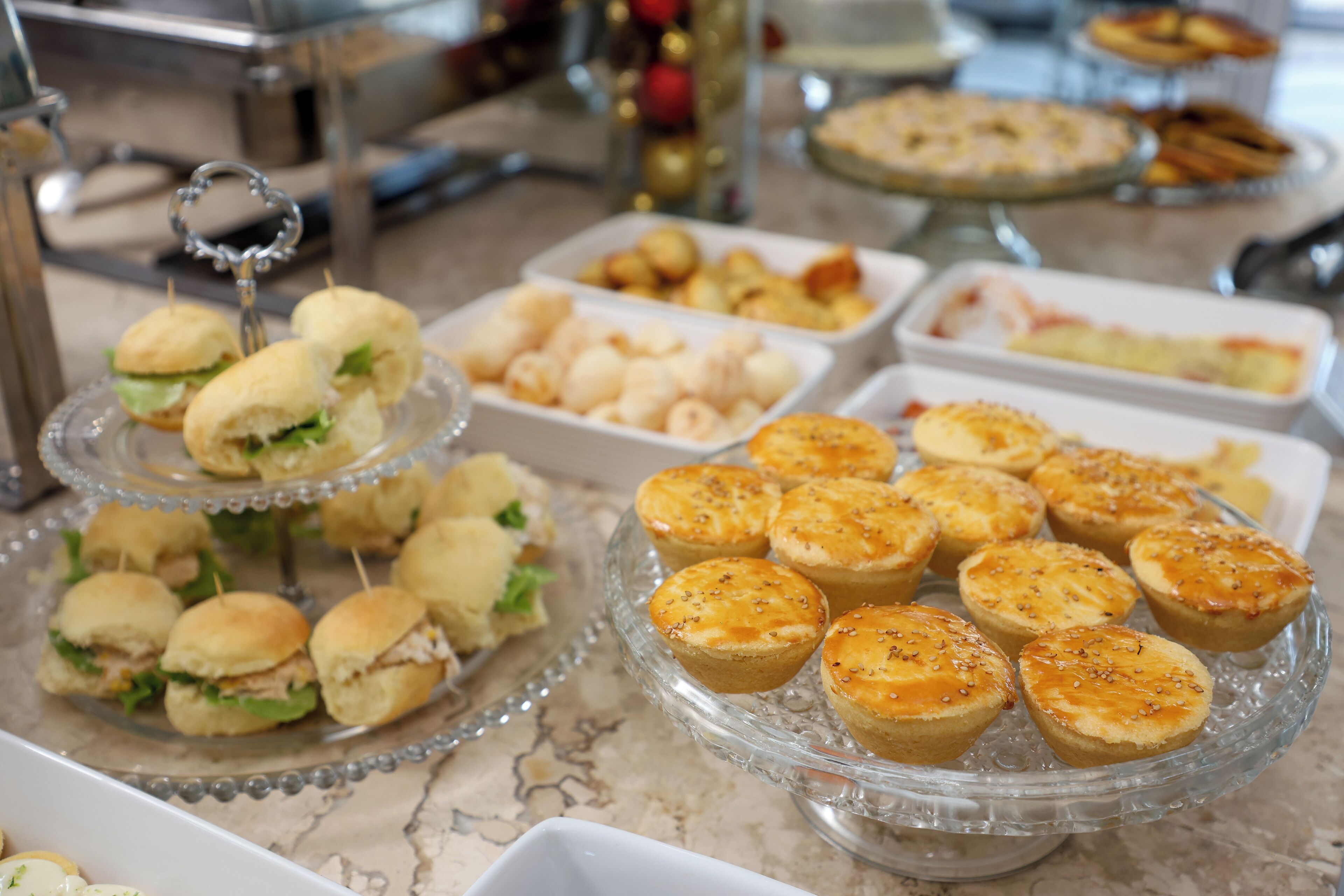Un bufé con diversos alimentos, incluyendo sándwiches, pasteles y postres.