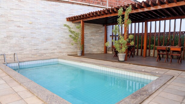 Une piscine rectangulaire dont les bords sont recouverts de carreaux, entourée d’une terrasse également carrelée.