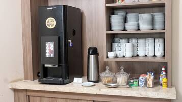 Una kitchenette con cafetera, repisas con platos y tazas, y un pequeño árbol de Navidad.