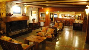 Un acogedor interior de cabaña con chimenea de piedra, muebles de madera y una zona de bar.