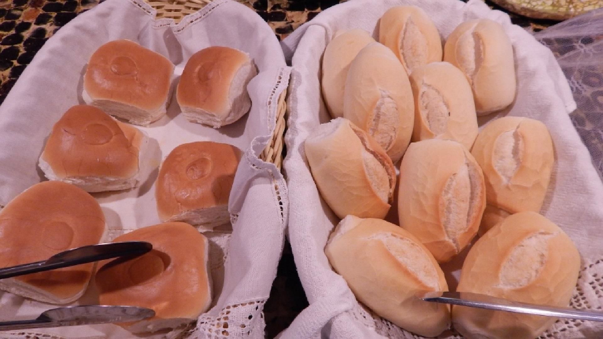 Two baskets of bread rolls, one with round buns and the other with elongated rolls, on a table.