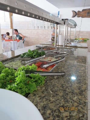A buffet setup with various food items and utensils. - Água Doce Praia Hotel (Ubatuba)