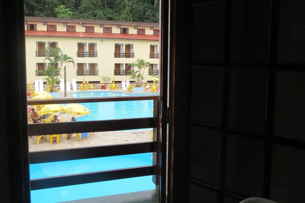 A balcony with a view of a swimming pool and a building with multiple windows and balconies.