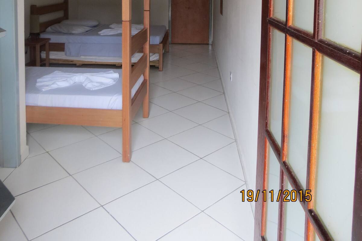 A corridor with bunk beds, a wooden door, and a tiled floor.