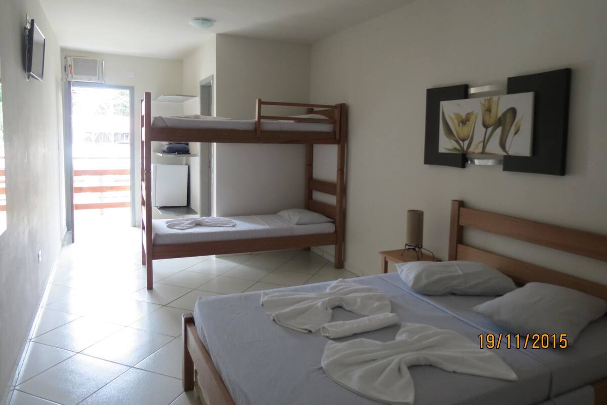 A bunk bed room with a desk, a small cabinet, and a picture on the wall.