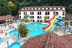 A resort with multiple swimming pools, a water slide, and a building with balconies. - Água Doce Praia Hotel (Ubatuba)