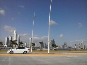 A cityscape with modern high-rise buildings, a white car on the road, and street lamps. - Voyager Int'l Hostel Panamá City (Panama City)
