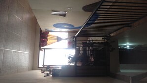 A room with a sloped ceiling, a window with curtains, a fan, and a metal shelf with various items. - Voyager Int'l Hostel Panamá City (Panama City)