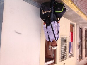 A person hanging upside down with backpacks on a building's exterior wall. - Voyager Int'l Hostel Panamá City (Panama City)