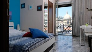 A bedroom with a bed, a desk, and a balcony with a city view. - B&B Il Golfo (Naples)