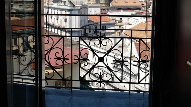 A balcony with wrought iron railings overlooking a cityscape with a prominent dome building. - B&B Il Golfo (Naples)