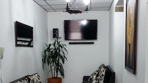 A room with two black sofas, a potted plant, a flat-screen TV, and a sign reading "LOBB". - Hotel Europa (Bogota)