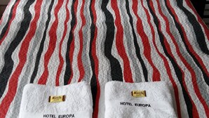 A bed with striped bedding and two towels labeled "HOTEL EUROPA". - Hotel Europa (Bogota)