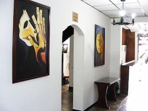 A hallway with two paintings on the walls, a wooden bench, and a door leading to another room. - Hotel Europa (Bogota)