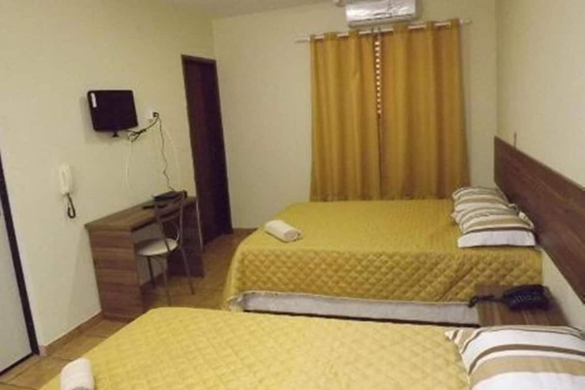 Une chambre d’hôtel avec deux lits, un bureau, une chaise, une télévision et un rideau.