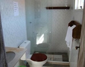 A small bathroom with a toilet, a shower, and a sink. - Pousada La Lampara (Cabo Frio)