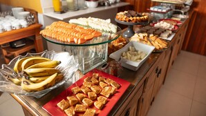 A buffet with various food items including bananas, cheese, and pastries. - Castelo Piazzale by Concavus (Campos do Jordao)