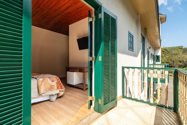 Ein Zimmer mit einem Bett, einem kleinen weißen Schrank und einer Holzbalkendecke.