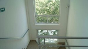 Una escalera con barandillas metálicas y vistas a árboles a través de amplios ventanales.