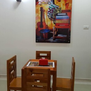 A dining area with a wooden table and chairs, a poster on the wall, and a red object on the table.