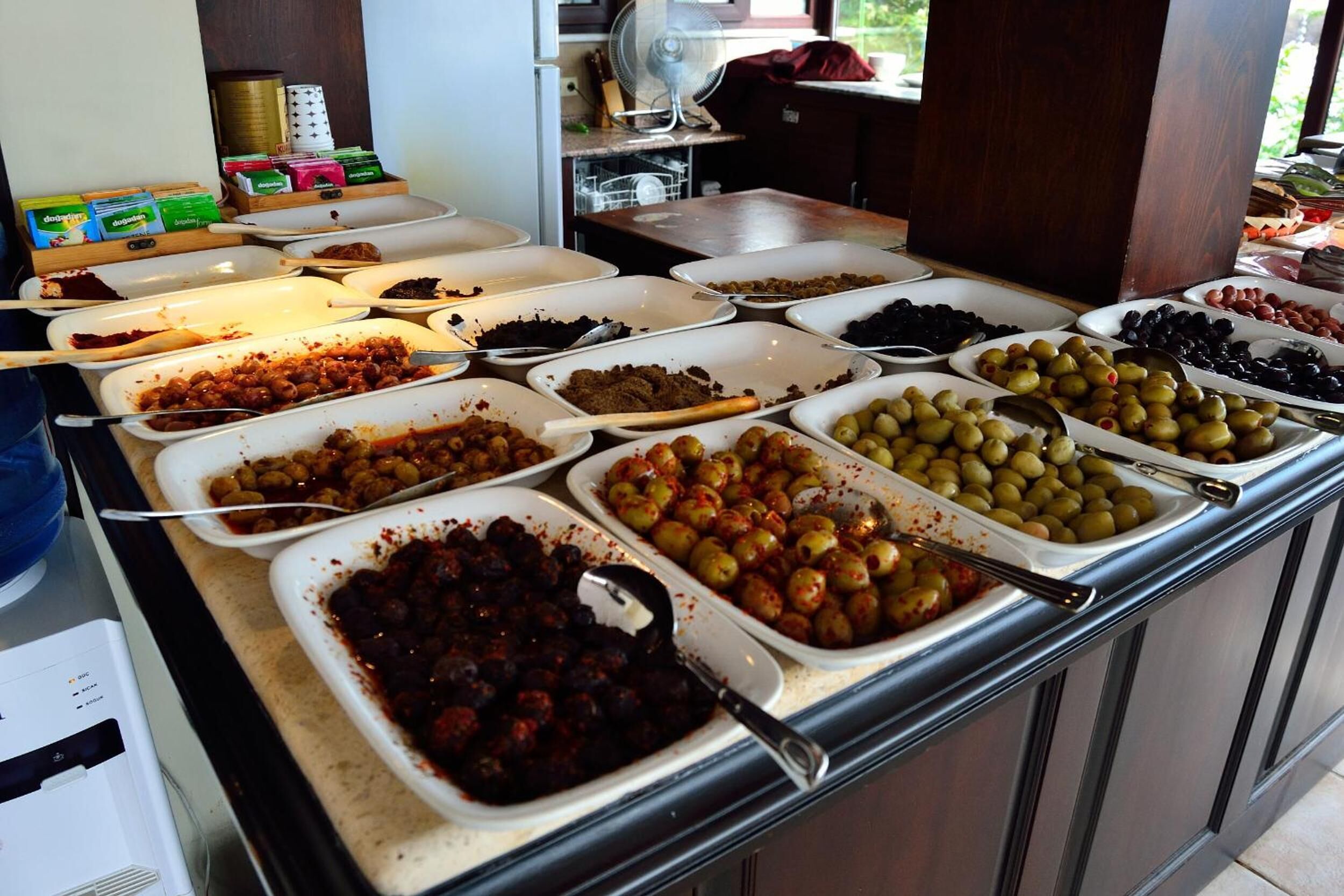 A buffet with various food items including olives, meats, and sauces.