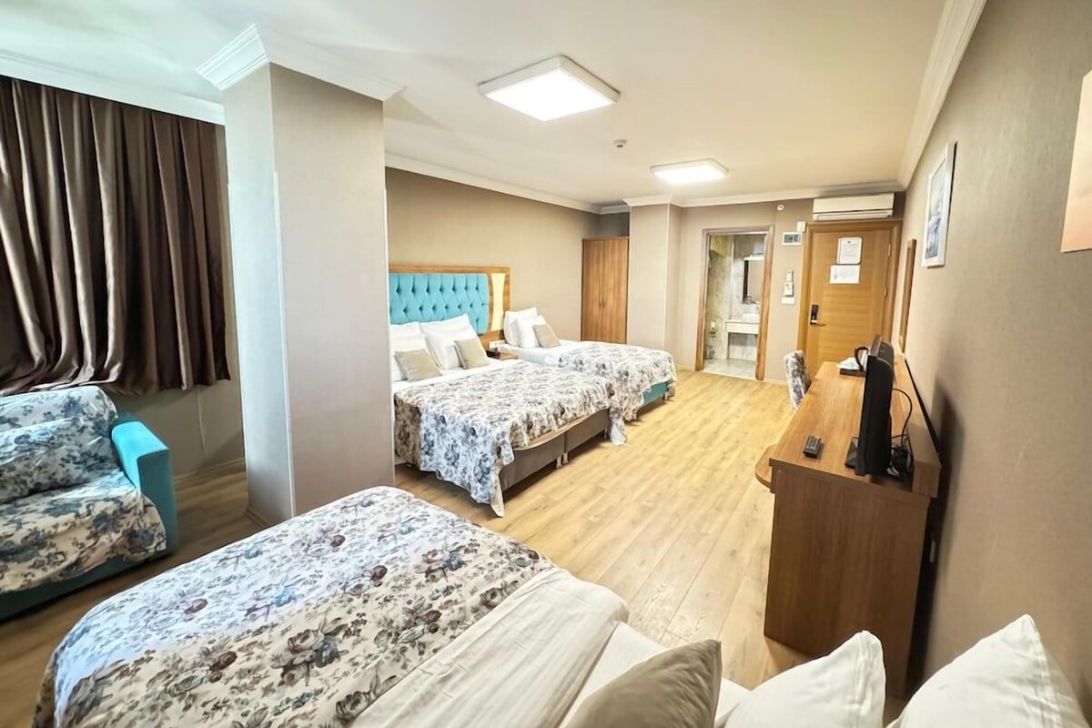 A hotel room with two beds, a desk, a chair, and a bathroom visible through an open door.